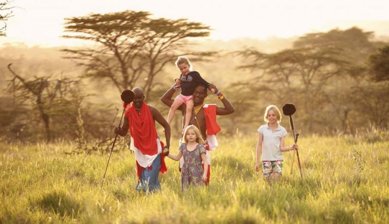 Family with children in an open safari vehicle watching animals in the Serengeti.