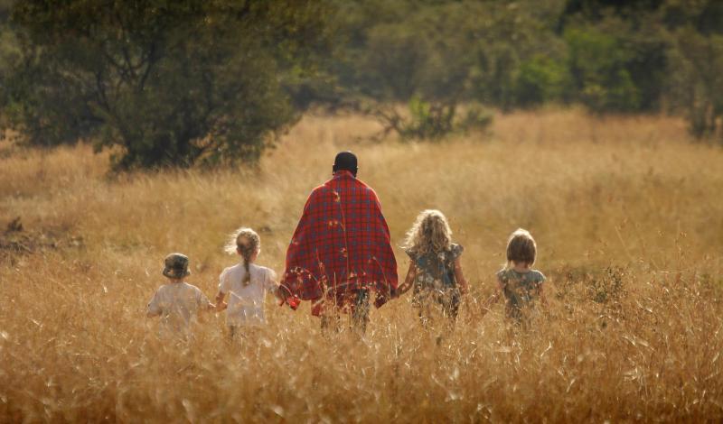 Child with binoculars looking intently into the distance during a family safari in Tanzania.
