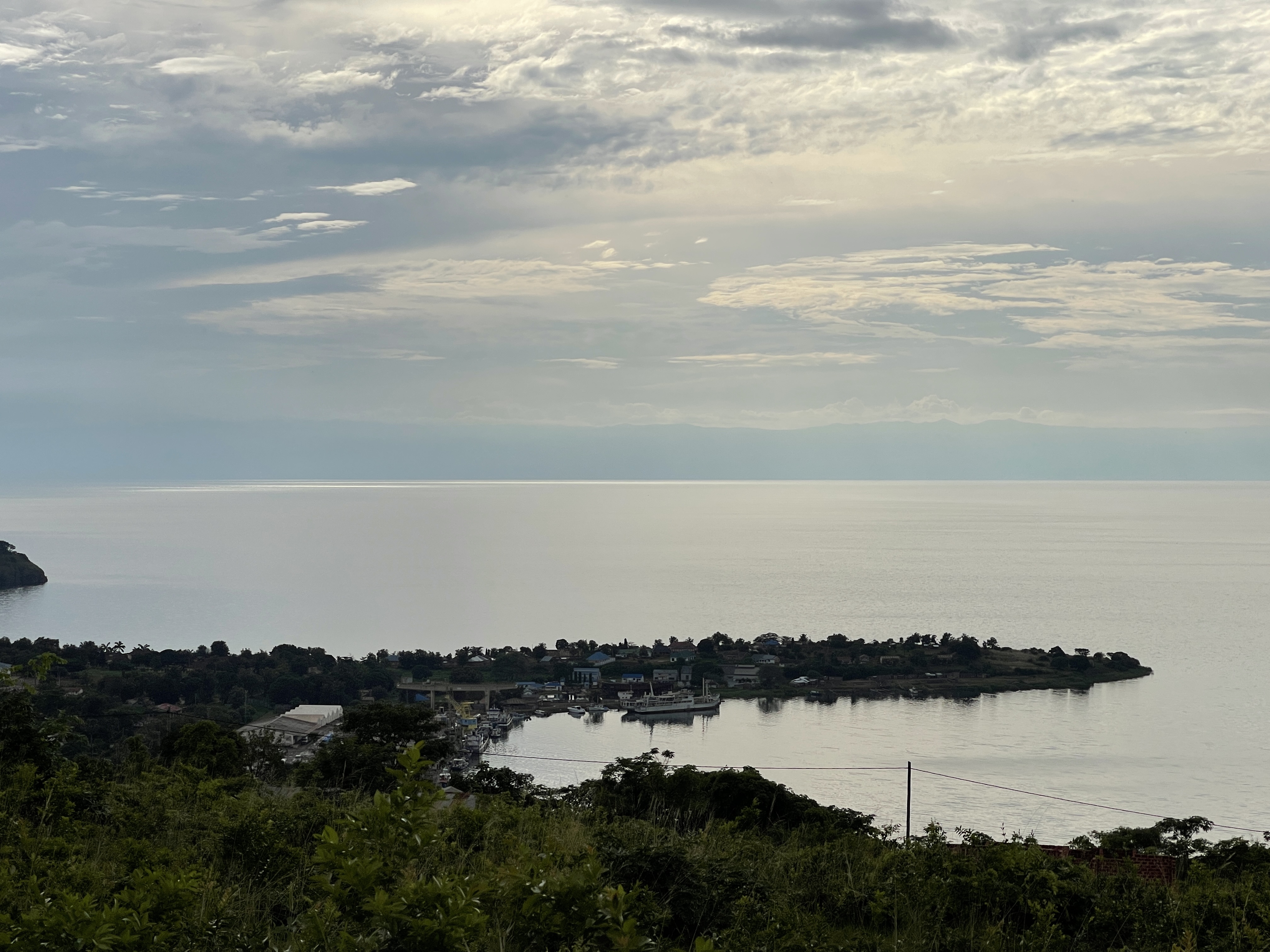 Wooden fishing boats on the shore of Lake Tanganyika near Kigoma, with misty mountains in the background.